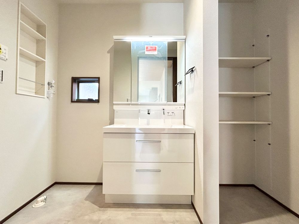 ホテルライクな洗面台は三面鏡裏に大容量の収納付き。日常使いのランドリー用品は埋込収納へ、それ以外は可動棚へ収納することで脱衣室回りもスッキリ。
