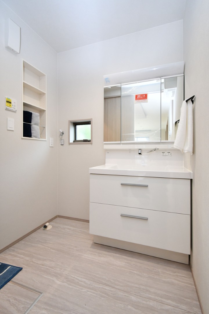 【洗面脱衣室｜埋め込み収納ですっきり整理】 洗濯機横には埋め込み式の収納スペースを設置。タオルや洗剤などをすっきり収められ、空間を無駄なく活用できます。