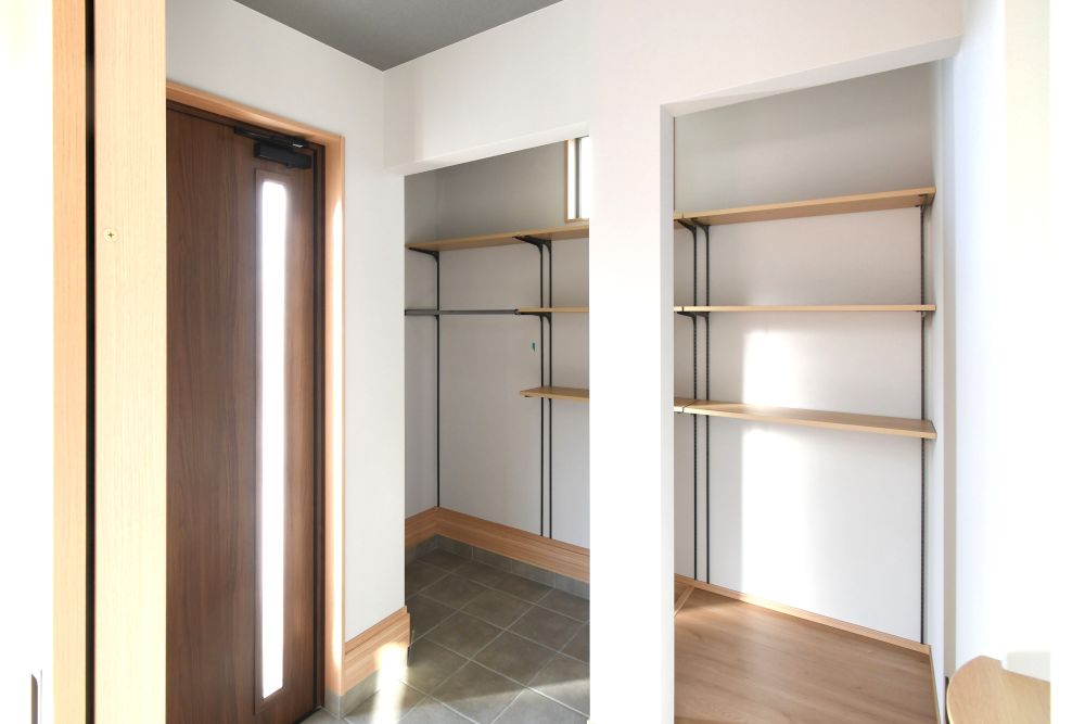 【シューズクローク付き玄関】玄関ドアを開けた瞬間に目を引くのは、壁面ニッチと柔らかな灯りの照明演出。シンプルな空間の中にさりげない“おもてなしの美意識”が感じられます。