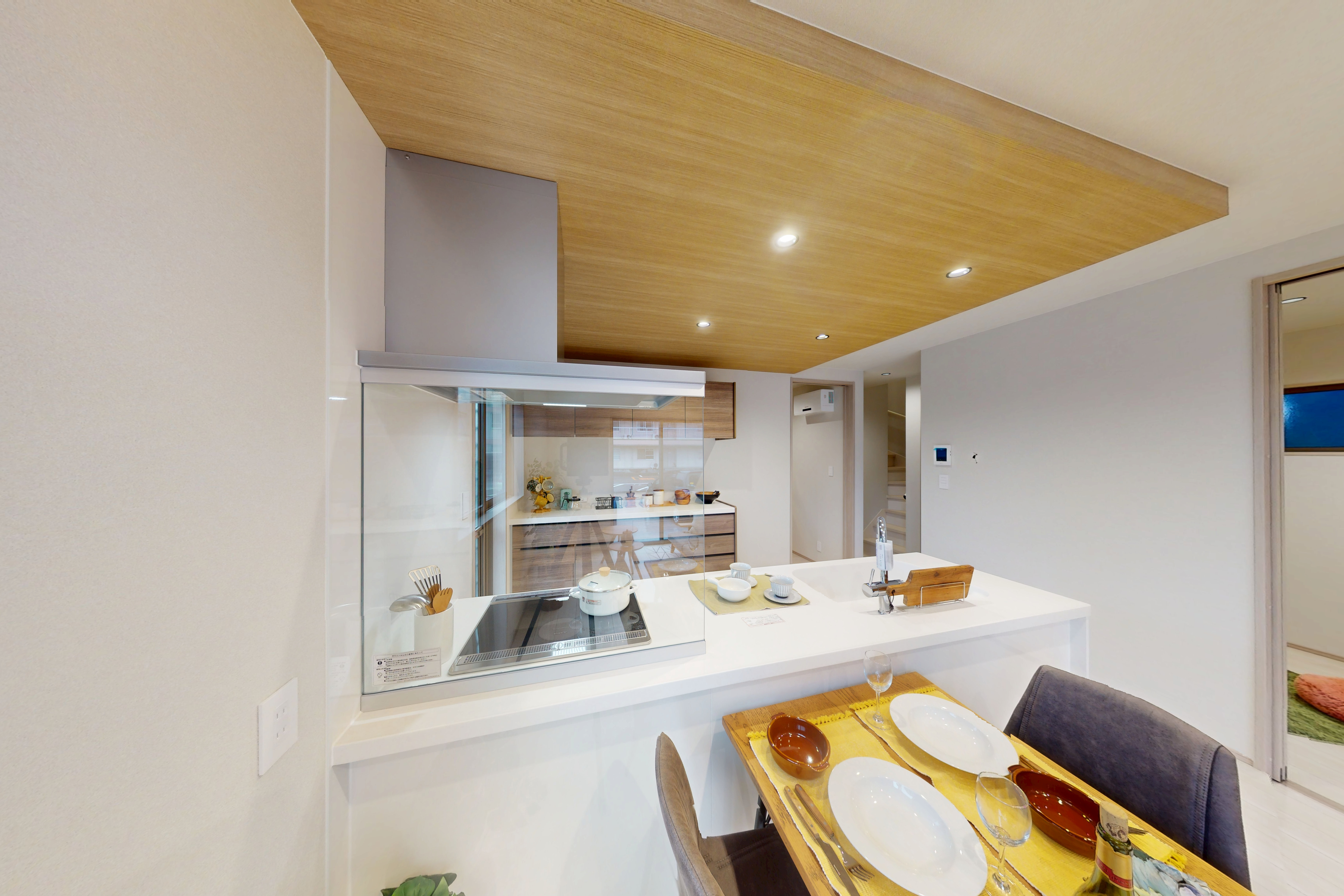 【空間に上質なニュアンスを添える折下げ天井】 折下げ天井には、モダンにもナチュラルにも映えるグレイッシュな木目調クロスを採用。空間にさりげないニュアンスと上質なアクセントを添えています。